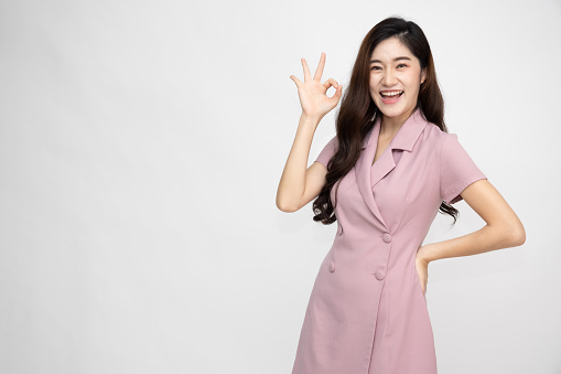 Asian woman smiling and showing OK sign isolated on white background