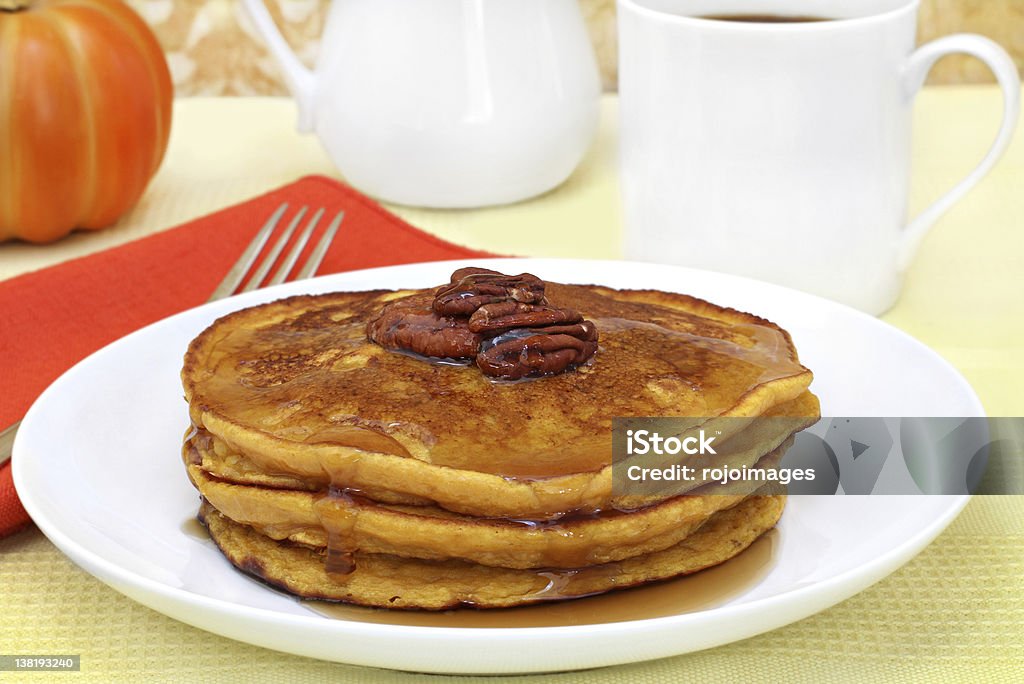 Pumpkin pancakes with pecans and syrup. Stacked pumpkin pacakes with maple syrup and fresh pecans. Autumn Stock Photo