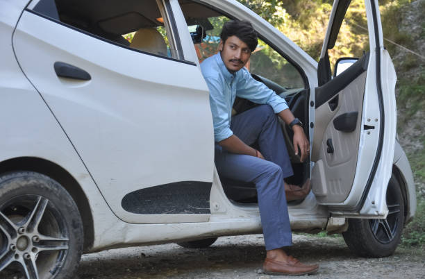 istock A handsome young Indian guy looking sideways while sitting in the car with open door 1381966189