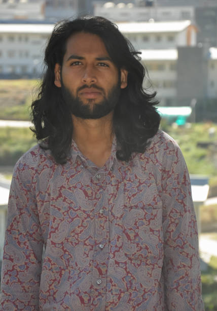 istock Portrait of a long haired and bearded good looking young man looking sideways while standing outdoor 1381969053