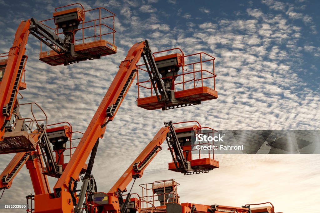 Articulated boom lift. Aerial platform lift. Telescopic boom lift against blue sky. Mobile construction crane for rent and sale. Maintenance and repair hydraulic boom lift service. Crane dealership. Equipment Stock Photo
