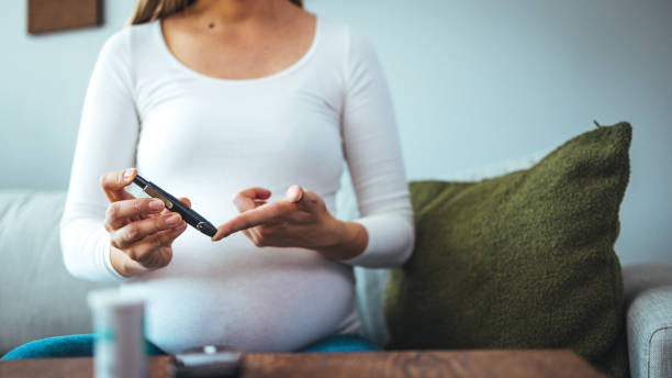 una mujer embarazada usa lanceta en el dedo para verificar el nivel de la prueba de azúcar en la sangre mediante un medidor de glucosa - diabetes human pregnancy women blood sugar test fotografías e imágenes de stock