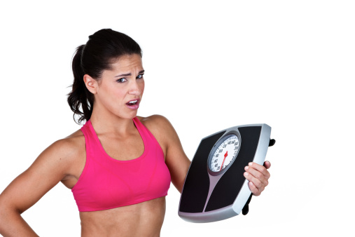 Woman holding a scale and an unhappy expression shot on white background 