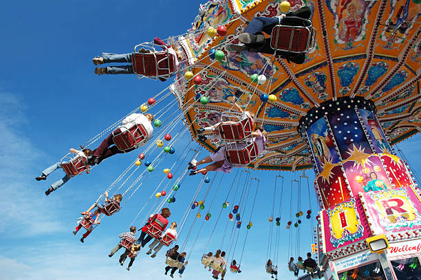 families at the fair on a swing ride - attractiepark fotos stockfoto's en -beelden