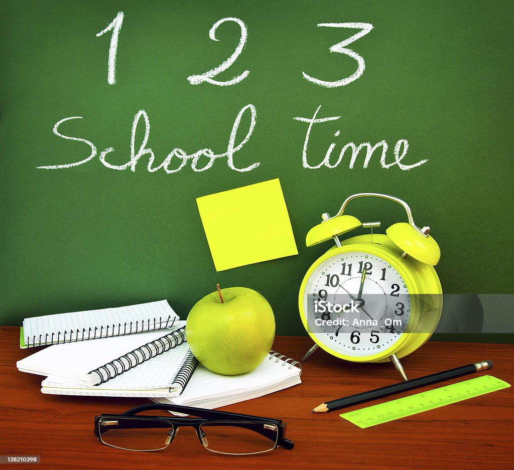 Back to school concept Back to school concept, green chalkboard with handwriting and set of colorful student accessories Alarm Clock Stock Photo