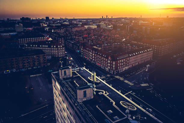 Cityscape over Copenhagen with commute traffic at Lyngbyvejen on Østerbro. 5G mast in foreground. Image captured by drone at dusk.