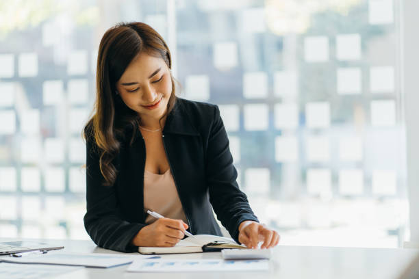 istock Asian business woman financial manager taking notes when working on report 1382125985