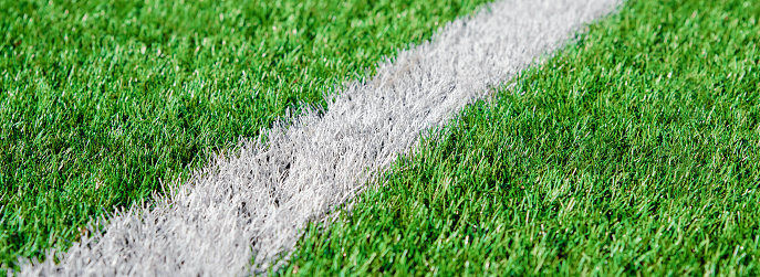 Part of football or soccer field close up, Artifical green grass with white border lines, Astroturf at stadium for spart games