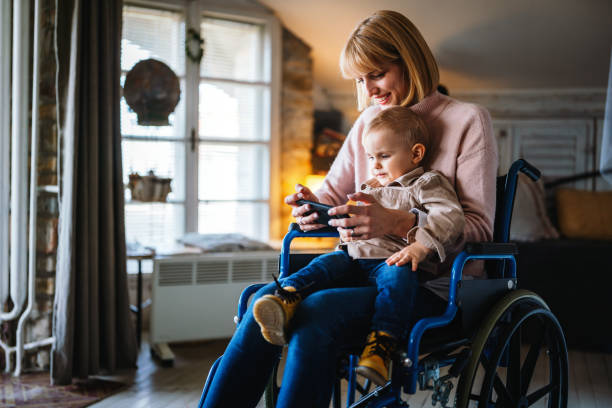 szczęśliwa matka na wózku inwalidzkim z dzieckiem za pomocą cyfrowego tabletu w domu. ludzie koncepcja szczęścia rodzinnego. - ipad baby boys little boys caucasian zdjęcia i obrazy z banku zdjęć