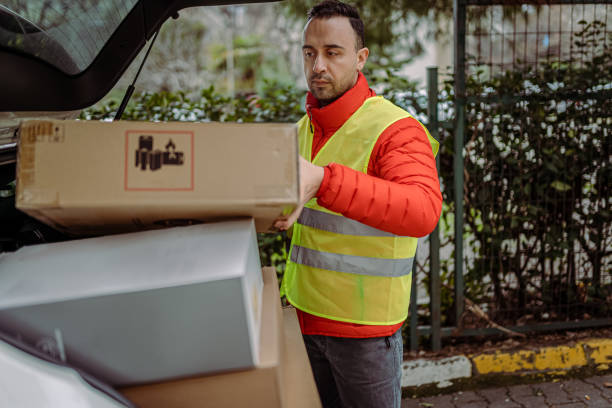 istock Young man courier by a delivery car, carrying parcels. 1382153237