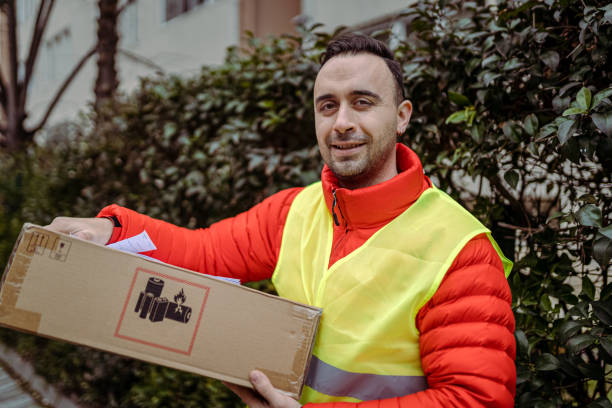 istock Young man courier by a delivery car, carrying parcels. 1382153815
