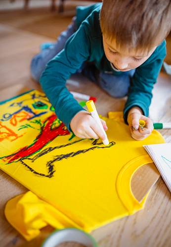 Young child drawing his own artwork on shirt at home