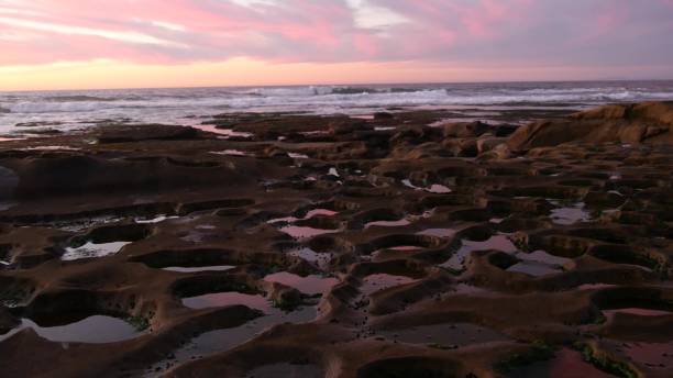 istock Eroded tide pool rock formation in California. Sunset sky reflection in water. 1382160569
