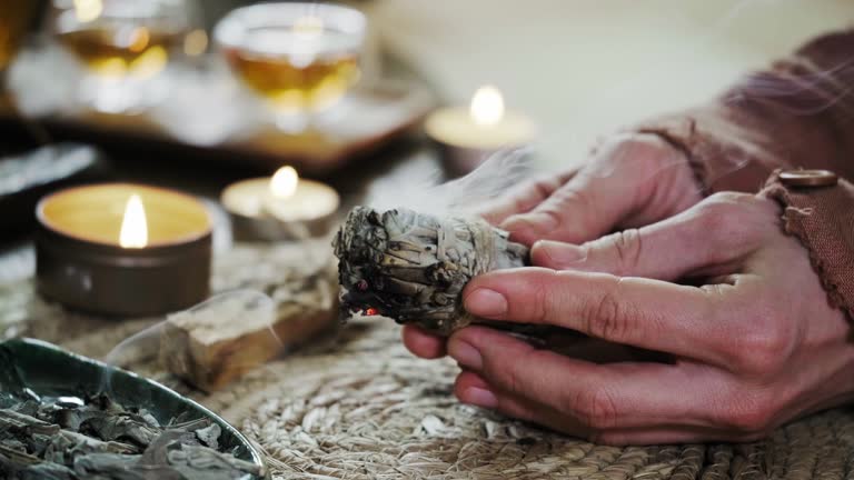 Woman hands burning white sage, before ritual on cadle