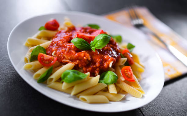 komposition mit einem teller pasta penne rigate - penne rigatoni pasta tomato pasta stock-fotos und bilder