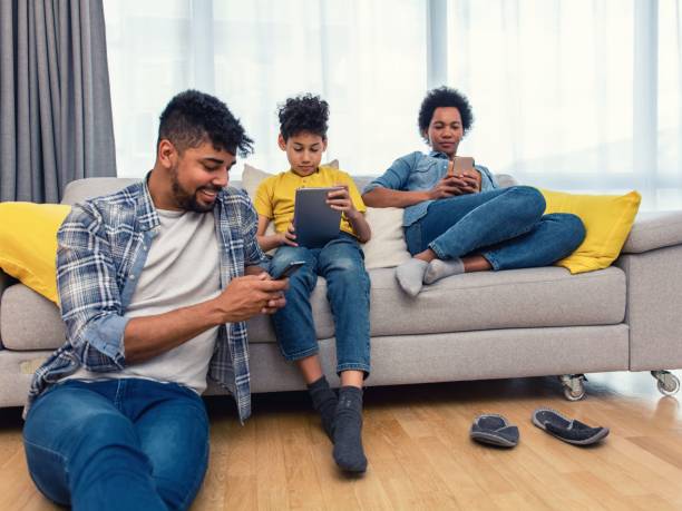 istock Black family relax on the couch using gadgets 1382186034