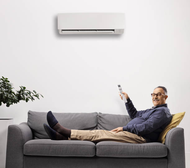 istock Mature man laying on a sofa and putting the air conditioning on with a remote control 1382187816