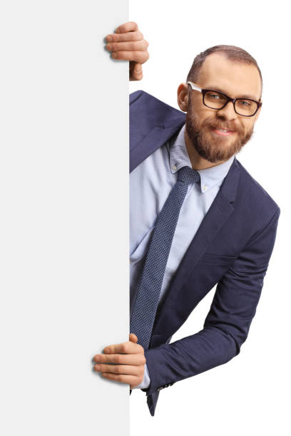 istock Young man with glasses peeking from behind a blank white panel 1382188306