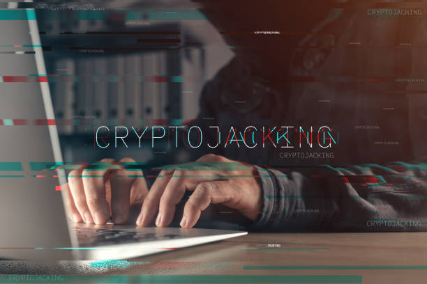 ラップトップコンピュータで動作する顔のないフードをかぶったハッカーとのクリプトジャッキングコンセプト - ��仮想通貨マイニング ストックフォトと画像
