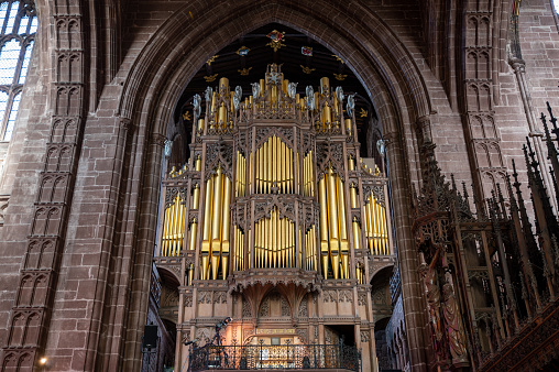 Golden pipe organ and ornate stonework inside a cathedral