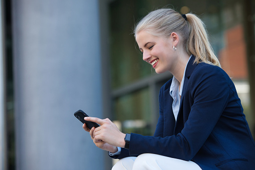 Modern  businesswoman sitting outside her office on her phone