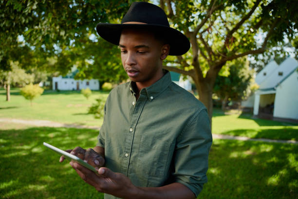 istock Mixed race male farmer standing outdoors typing on digital tablet 1382212715