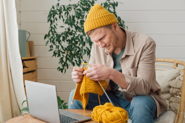 middle aged man learning knitting on needles. knitting project in progress. man learning a new hobby - tricotar imagens e fotografias de stock