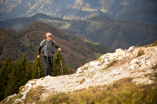Mature man hiking with hiking poles on mountain.