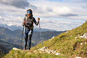 Woman hiking on mountain against cloudy sky