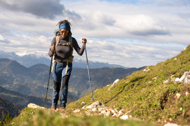 Woman hiking on mountain against cloudy sky stock photo