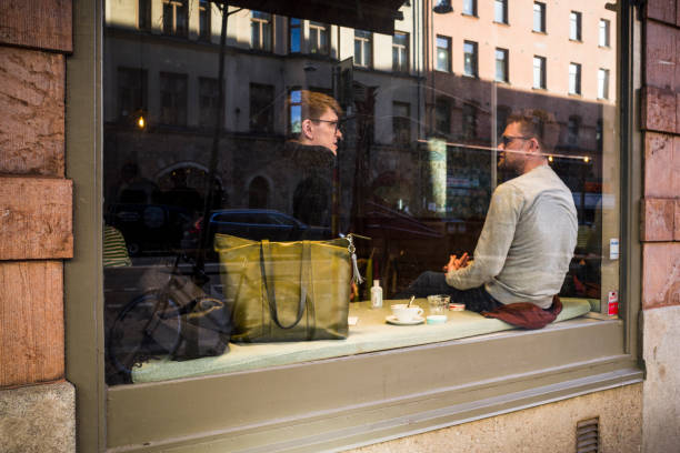 Stockholm, Sweden Feb 27, 2022 Two men sit in a cafe window on Hornsgatan on Sodermalm.