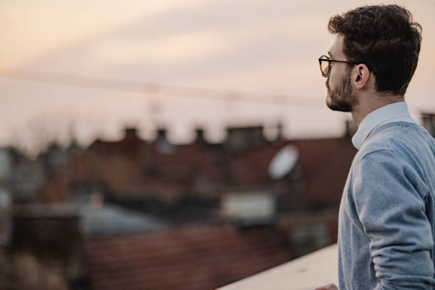 istock Young man relaxing on the rooftop and looking at view 1382235844