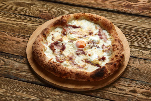 istock Carbonara pizza with bacon and egg on wooden background 1382237933