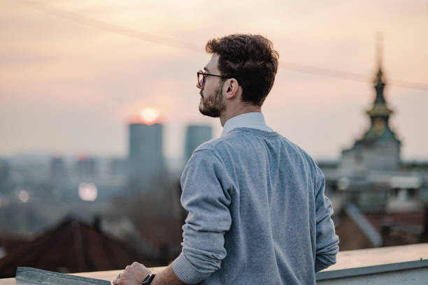 A young man is on the balcony at sunset