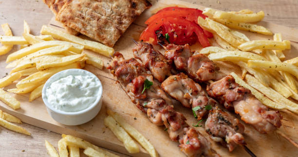 Souvlaki dish, Greek chicken meat food. Grilled skewers and pita bread on wooden table, overhead stock photo