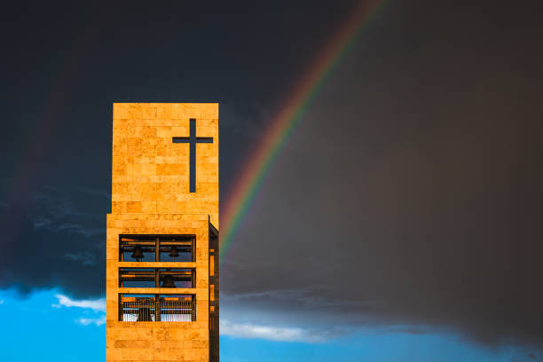 Rainbow and church with christian cross during a cloudy weather