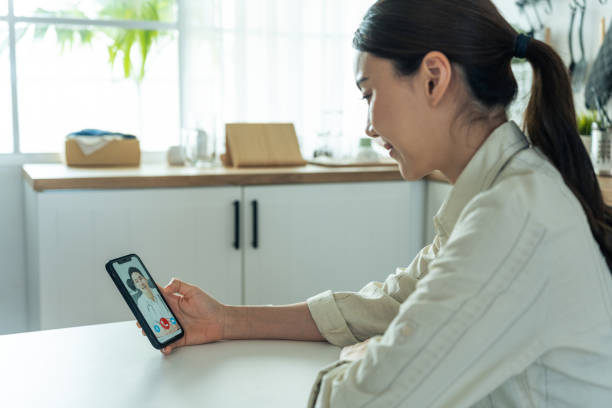 医師とオンラインで仮想を話すアジアの若い女性患者。自宅で病気の女の子にインターネット相談診断治療のための遠隔医療遠隔医療ビデオコールを与える魅力的な医師の男性。 - オンライン診療 スマホ 日本人 ストックフォトと画像
