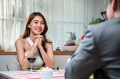 一緒にバレンタインデーを祝うために夕食を食べるアジアの若いカップル。魅力的なロマンチックな新しい結婚の男女の夜のパーティーは、自宅の台所で結婚記念日のためにテーブルの上に�
