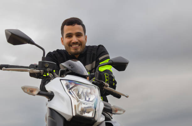 istock hispanic guy dressed in biker jacket riding his motorcycle while smiling and looking at the camera 1382265348