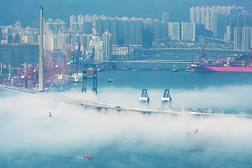 Cargo port and bridge in harbor of Hong Kong city in fog