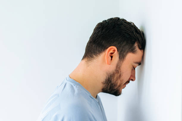 istock Side view of an unhappy man resting head against office wall. 1382265999
