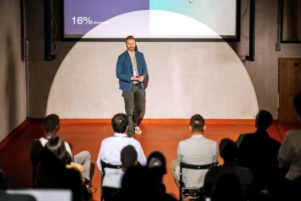 istock Young casually clothed speaker holding a presentation in front of a crowd 1382268678