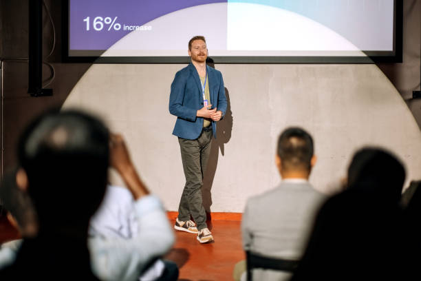 istock Young casually clothed speaker holding a presentation in front of a crowd 1382268708