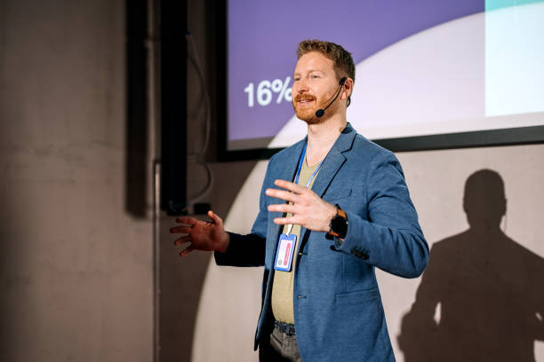 istock Young casually clothed man giving a speech on a conference 1382268924