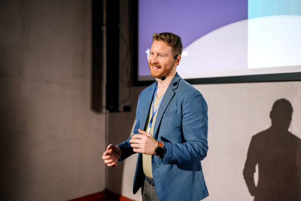 Young casually clothed man giving a speech on a conference