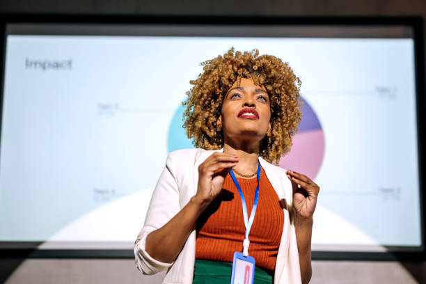 lässig gekleidete hipster-frau hält eine rede auf einer konferenz - bildschirmpräsentation stock-fotos und bilder