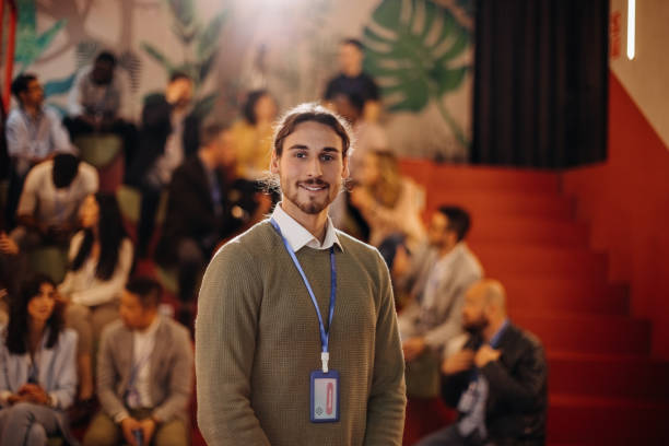 istock Young male conference presenter posing in front room full of audience 1382270206