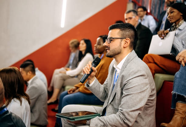 istock Well dressed young man asking presenter a question while attending business conference 1382270208