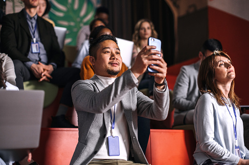 Young well dressed man taking a photo while attending business conference