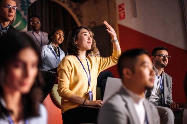 Young beautiful woman asking a question during business conference